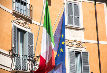 European flag and Italian flag hanging on a balcony in Italy during daytime. Europe.