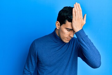 Handsome hispanic man wearing turtleneck sweater surprised with hand on head for mistake, remember error. forgot, bad memory concept.