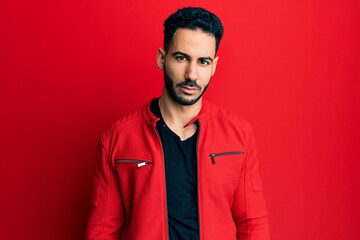Young hispanic man wearing red leather jacket looking sleepy and tired, exhausted for fatigue and hangover, lazy eyes in the morning.