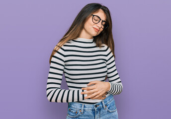 Young beautiful teen girl wearing casual clothes and glasses with hand on stomach because indigestion, painful illness feeling unwell. ache concept.