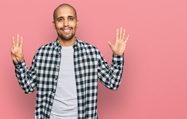 Naklejka premium Hispanic adult man wearing casual clothes showing and pointing up with fingers number eight while smiling confident and happy.