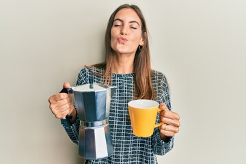 Young beautiful woman drinking italian coffee looking at the camera blowing a kiss being lovely and sexy. love expression.