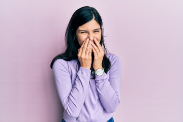 Young hispanic woman wearing casual clothes laughing and embarrassed giggle covering mouth with hands, gossip and scandal concept