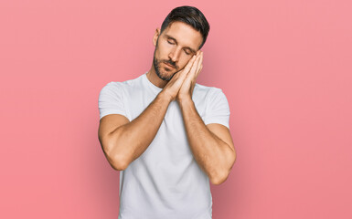 Handsome man with beard wearing casual white t shirt sleeping tired dreaming and posing with hands together while smiling with closed eyes.