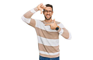 Handsome man with beard wearing casual clothes and glasses smiling making frame with hands and fingers with happy face. creativity and photography concept.
