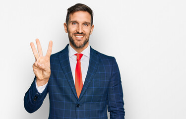 Handsome man with beard wearing business suit and tie showing and pointing up with fingers number three while smiling confident and happy.