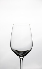 Close up and Front view of clear empty wine glass with beautiful lighting and white background shows elegant crystal glassware for luxurious beverage in restaurant, winery and celebrating party.