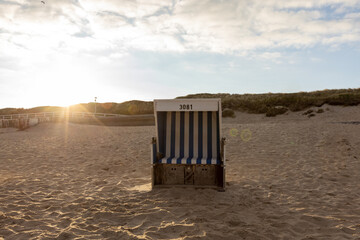 Sylt island beach landscape with empty beach chair and fine sand on the North Sea, at sunset. Sun...