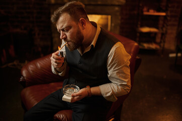 Bearded man with ashtray lights a cigarette