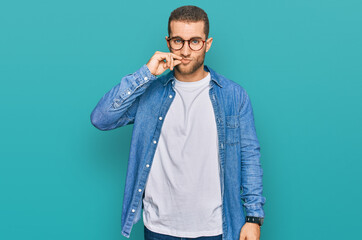 Young caucasian man wearing casual clothes mouth and lips shut as zip with fingers. secret and...