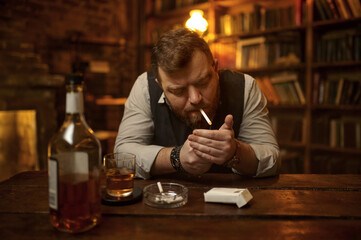 Man smokes cigarette and drinks alcohol beverage