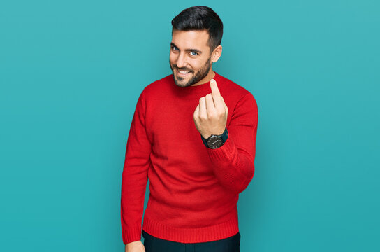 Young hispanic man wearing casual clothes beckoning come here gesture with hand inviting welcoming happy and smiling