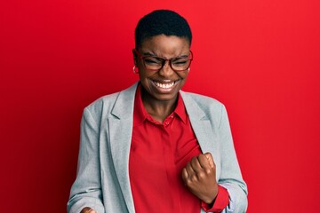 Young african american woman wearing business jacket and glasses very happy and excited doing...