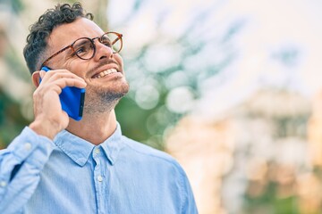 Young hispanic businessman smiling happy talking on the smartphone at the city.