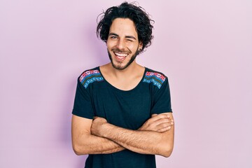 Handsome hispanic man with arms crossed gesture winking looking at the camera with sexy expression, cheerful and happy face.
