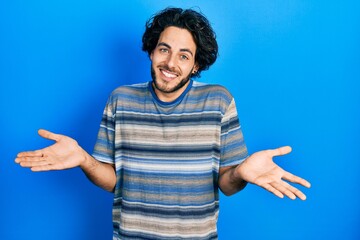 Handsome hispanic man wearing casual clothes over pink background clueless and confused expression...