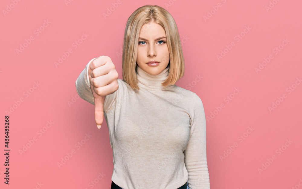 Wall mural young blonde woman wearing casual clothes looking unhappy and angry showing rejection and negative w