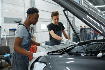 Two male mechanics checking motor, car service