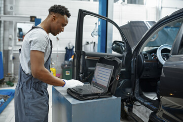 Male mechanic using laptop, car service