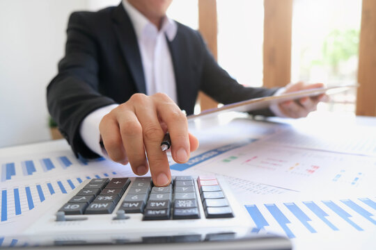 asian business meeting with hand pointing graph discussion and analysis data charts and graphs and using a calculator to calculate  numbers.Business finances and accounting concept