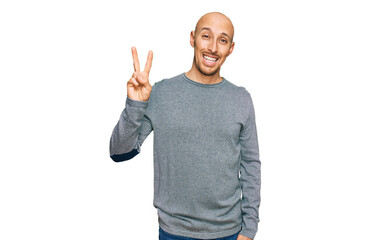 Bald man with beard wearing casual clothes showing and pointing up with fingers number two while smiling confident and happy.