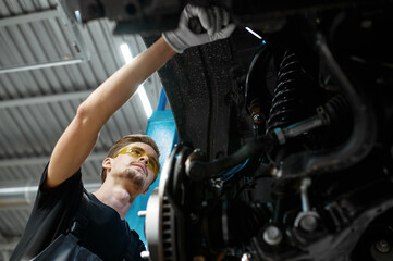 Male mechanic checks car suspension, auto service