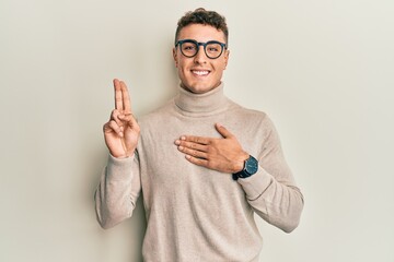 Hispanic young man wearing casual turtleneck sweater smiling swearing with hand on chest and fingers up, making a loyalty promise oath