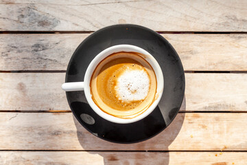 top view cappuccino with sweet foam in ceramic cup with black saucer