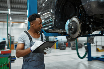 Male worker checks car brakes, auto service