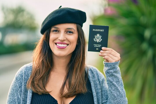 Young latin woman wearing french style holding usa passport at the city.