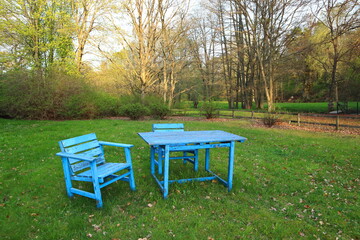 Blue furniture outside against a green lawn during the spring. Sunny weather and a forest in the background. Lifestyle at the countryside. Stockholm, Sweden.