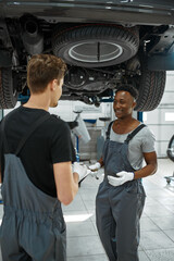 Male mechanics looking on checklist, car service