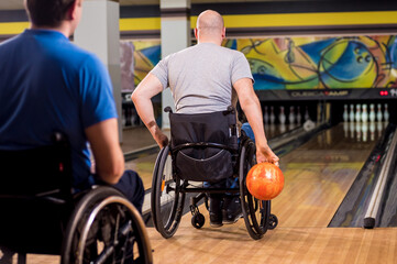 Two young disabled men in wheelchairs playing bowling in the club