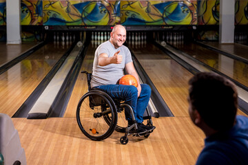 Two young disabled men in wheelchairs playing bowling in the club