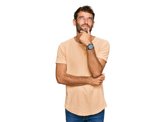 Handsome young man with beard wearing casual tshirt with hand on chin thinking about question, pensive expression. smiling and thoughtful face. doubt concept.