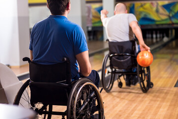 Two young disabled men in wheelchairs playing bowling in the club