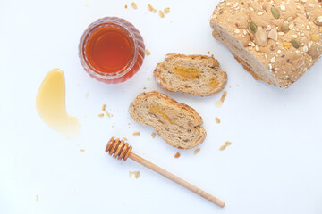 Sliced whole grain bread with oat flakes and honey on white