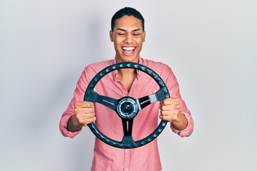 Young african american guy holding steering wheel smiling and laughing hard out loud because funny...