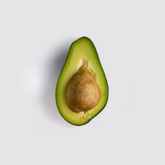 Half a green ripe avocado fruit with stone inside. Isolated on light-gray background