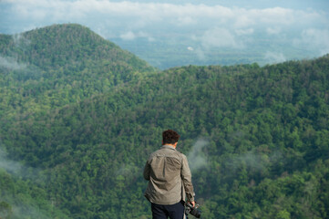 Naklejka premium Man photographer taking photographs with digital camera in a mountains. Creative professional photographing. Travel, hobby and active lifestyle concept