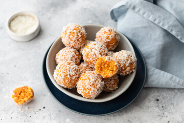 apricot coconut bliss balls in blue bowl on gray background. raw vegan dessert without sugar....