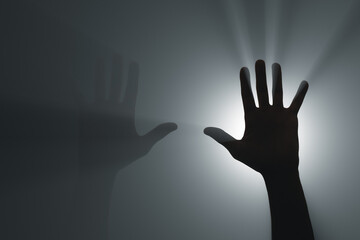 Silhouette of raised hands in the rays of the spotlight.