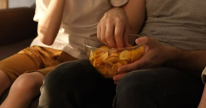 Men's and children's hands take chips from a bowl