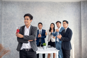 Businessman holding up a winning trophy Many hands applauding behind, Business concept