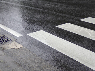 雨に濡れた横断歩道のあるアスファルトの道路