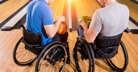 Two young disabled men in wheelchairs playing bowling in the club