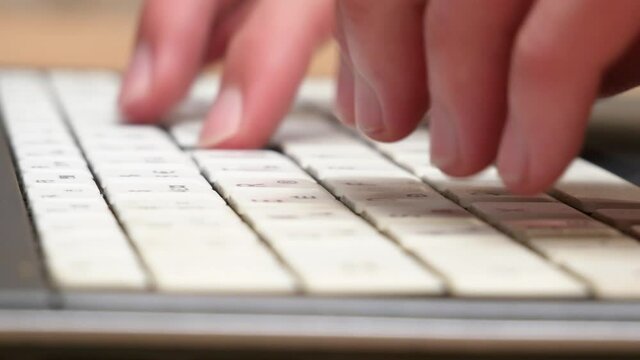 Hands, fingers fast typing on a white laptop keyboard, side view, computer keys extreme closeup, shallow dof. Man working on a netbook, chatting or messaging, writing online messages concept