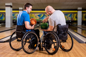 Two young disabled men in wheelchairs playing bowling in the club