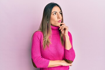 Young hispanic woman wearing casual clothes thinking concentrated about doubt with finger on chin and looking up wondering