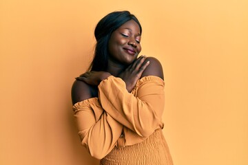 African young woman wearing casual clothes hugging oneself happy and positive, smiling confident. self love and self care - Powered by Adobe